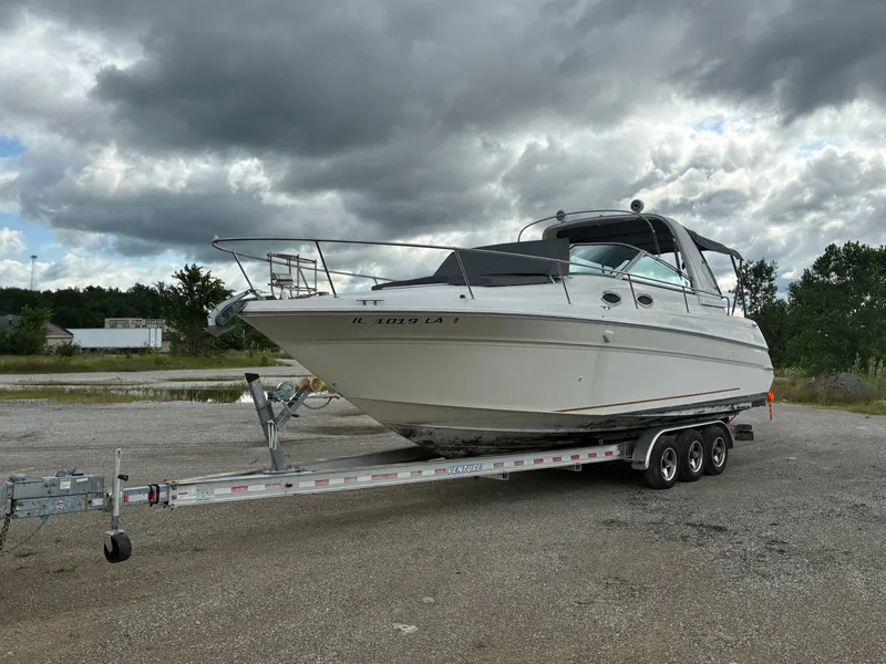 Slide: The Image of A 1998 Sea Ray 290 Sundancer on a trailer under a cloudy sky. - 1