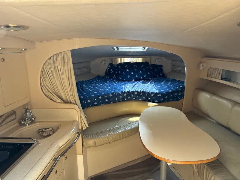Slide: The Image of Interior of a 1998 Sea Ray 290 Sundancer with kitchenette, dining table, and sleeping area. - 14