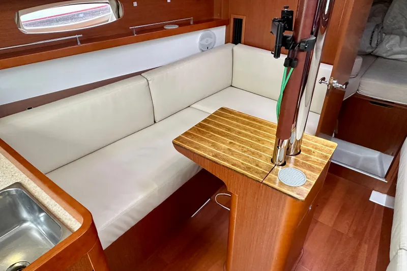 Slide: The Image of Interior of 2015 Beneteau Oceanis 31 yacht with cozy seating and wooden table. - 13