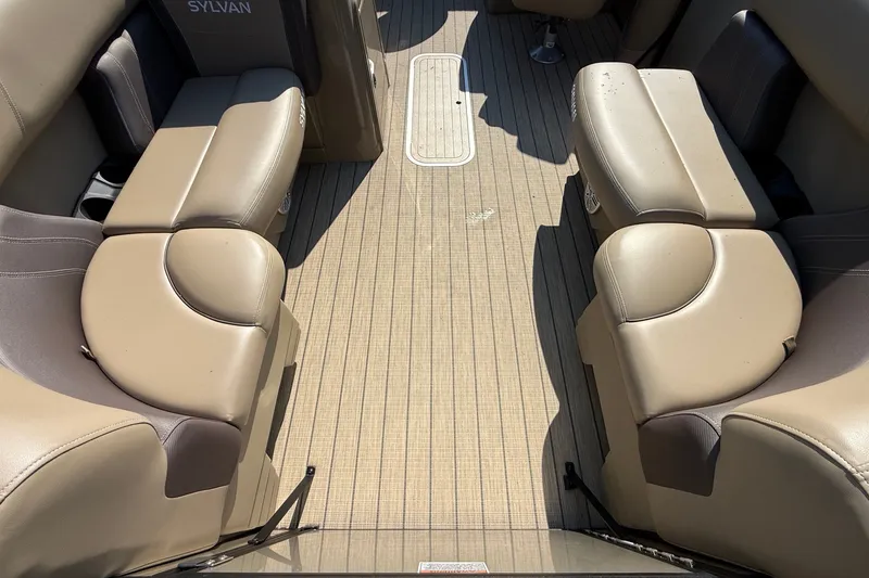 Slide: The Image of 2023 Sylvan Mirage X X1 boat interior with beige seating and wood-patterned flooring. - 11