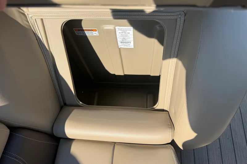 Slide: The Image of 2023 Sylvan Mirage X X1 storage compartment with beige upholstery and warning labels. - 44