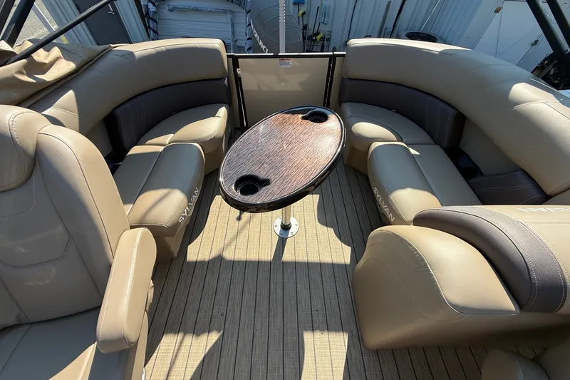 Slide: The Image of 2023 Sylvan Mirage X X1 boat interior with beige seating and wooden table. - 14