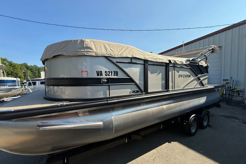 The Image of 2023 Sylvan Mirage X X1 pontoon boat with cover, parked on a trailer. - 1