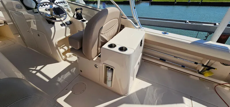 Slide: The Image of 2014 Grady-White Freedom 285 boat interior with helm, seating, and cup holders by the water. - 12