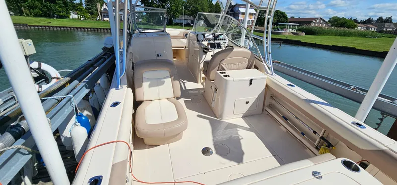 Slide: The Image of 2014 Grady-White Freedom 285 boat interior, featuring seating and controls, docked by a serene waterfront. - 5