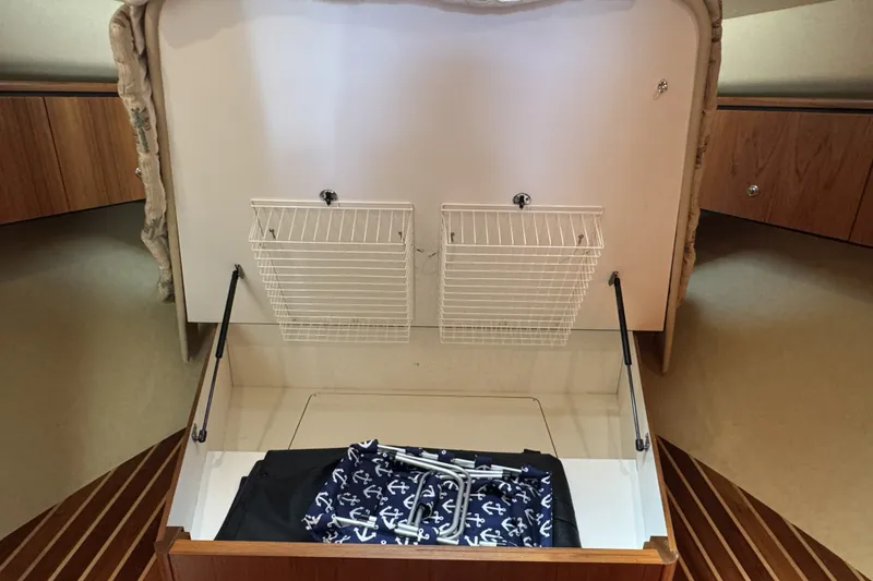 Slide: The Image of Storage compartment in 2008 Tiara Yachts 4300 Sovran, featuring wire baskets and nautical-themed fabric. - 30