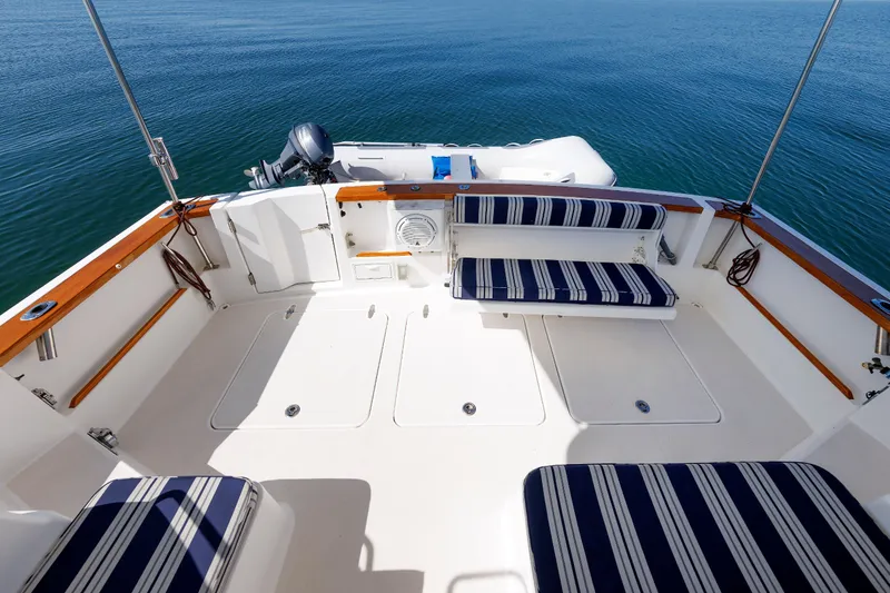 Slide: The Image of 2006 Sabre 42 Hard Top Express boat deck with striped seating, overlooking calm water. - 16