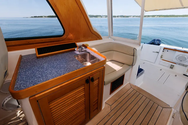 Slide: The Image of 2006 Sabre 42 Hard Top Express interior with kitchenette and seating, overlooking serene waters. - 23