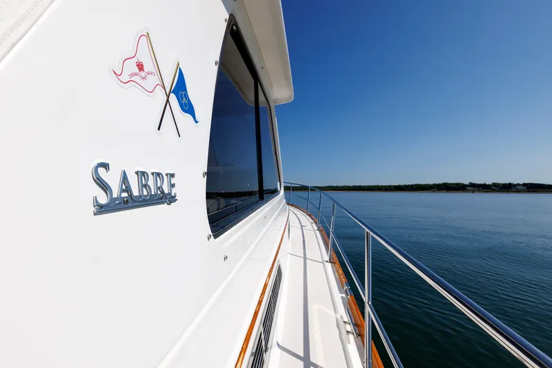 Slide: The Image of 2006 Sabre 42 Hard Top Express yacht cruising on calm waters under clear blue sky. - 46