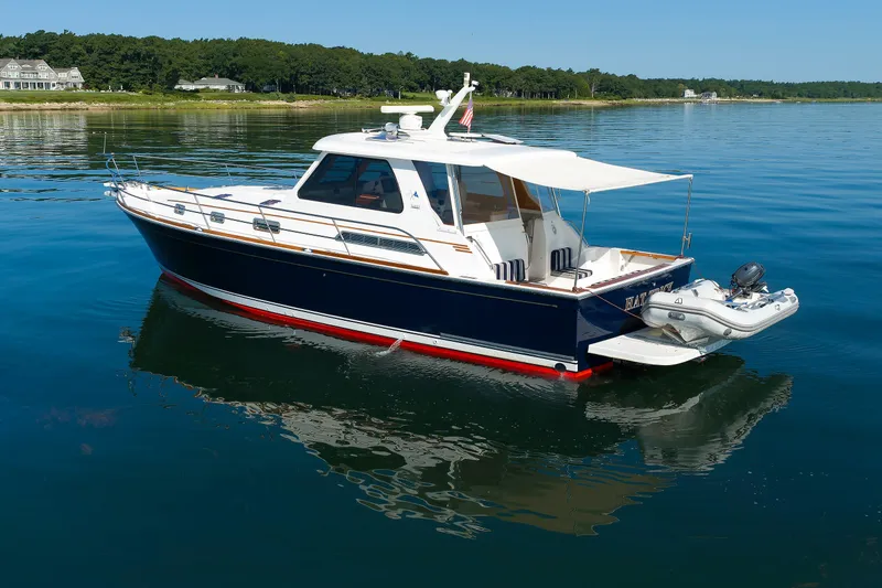 Slide: The Image of 2006 Sabre 42 Hard Top Express yacht on calm water, with scenic shoreline background. - 8