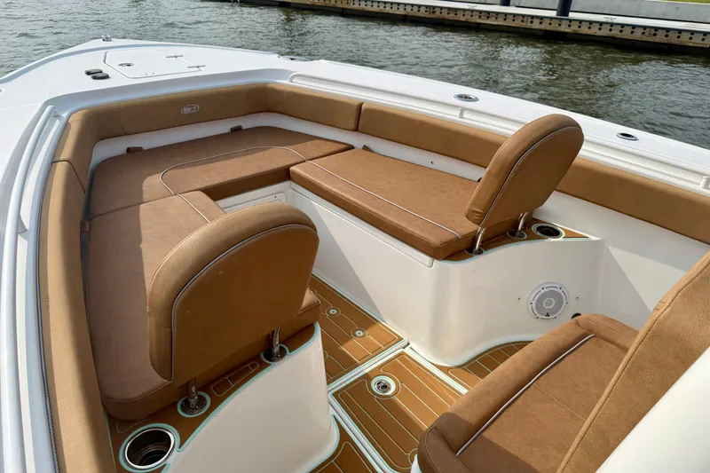 Slide: The Image of 2024 Sea Hunt Ultra 275SE boat interior with tan seating and wood-style flooring. - 18