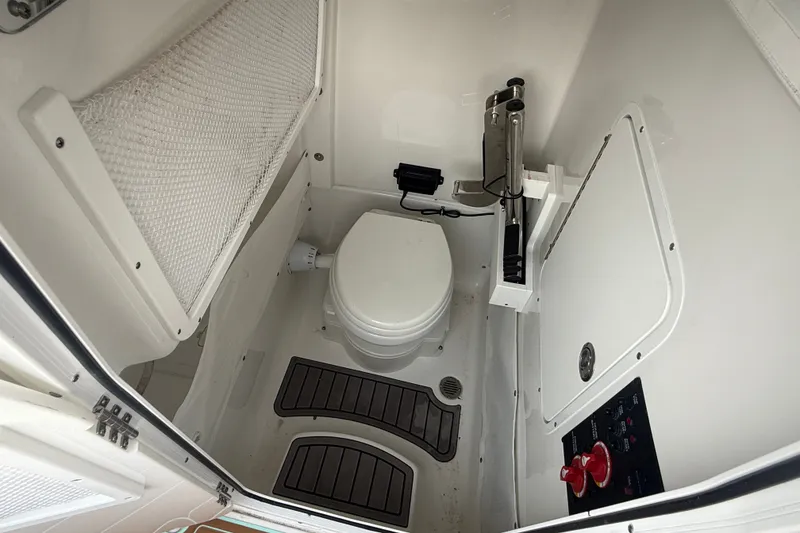Slide: The Image of 2024 Sea Hunt Ultra 275SE boat interior with compact marine toilet and storage. - 17