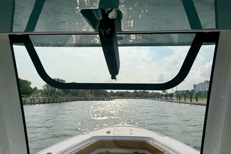 Slide: The Image of 2024 Sea Hunt Ultra 275SE boat cruising on a sunny waterway, viewed from the helm. - 16
