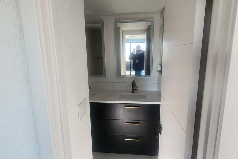 Slide: The Image of Modern bathroom with black vanity, gold faucet, and large mirror on Adonia Legacy Trip #15. - 20