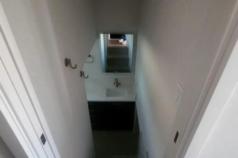 Slide: The Image of Narrow bathroom with sink and mirror, featuring hooks on the wall, Adonia Legacy Trip 2022. - 8