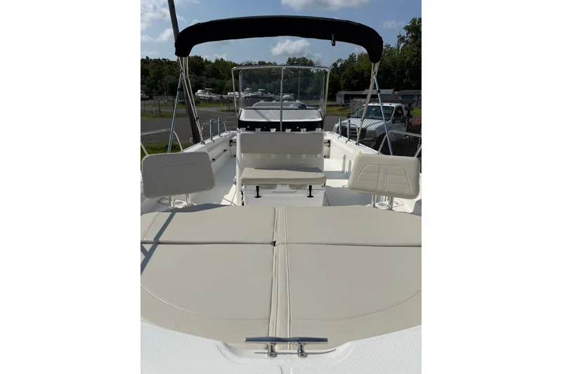 Slide: The Image of 2019 Boston Whaler 210 Montauk boat interior with seating and canopy, parked outdoors. - 6