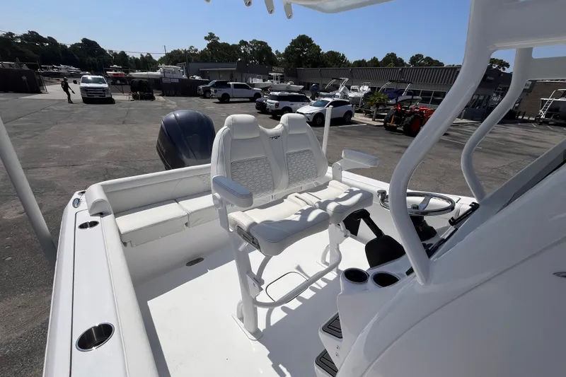 Slide: The Image of 2027 Tidewater 232 LXF boat interior with seating and steering console in a marina setting. - 15