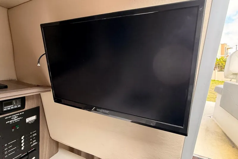 Slide: The Image of Flat-screen TV inside 2022 Regal 26 XO boat cabin, featuring control panel. - 8