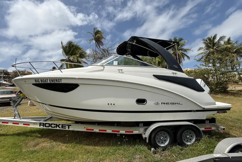 Slide: The Image of 2022 Regal 26 XO boat on trailer, palm trees in background, clear sky. - 1