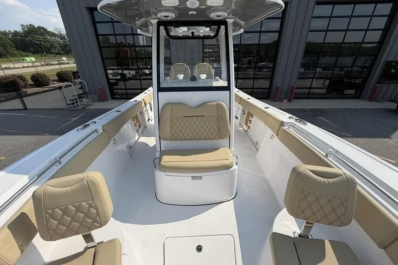 Slide: The Image of 2027 Sportsman Open 262 Center Console boat with beige seating, docked near a modern building. - 10