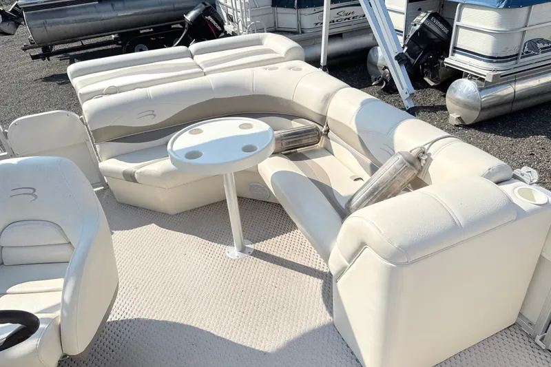 Slide: The Image of 2006 Bennington 2050GL pontoon boat interior with beige seating and round table. - 12