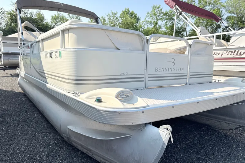The Image of 2006 Bennington 2050GL pontoon boat with canopy, parked on gravel, surrounded by trees. - 0