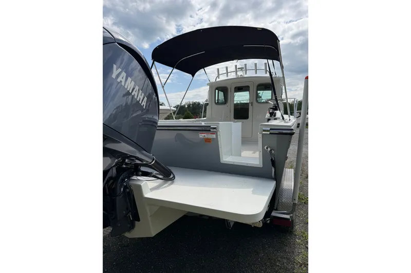 Slide: The Image of 2024 Parker 2320 Sport Cabin boat with Yamaha engine, rear view under cloudy sky. - 3