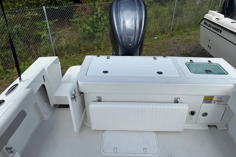 Slide: The Image of 2024 Parker 2320 Sport Cabin boat deck with storage compartments and outboard motor. - 7