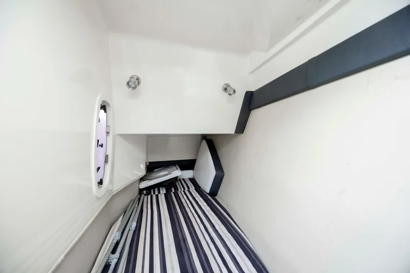 Slide: The Image of 2015 Monterey 328SS Super Sport cabin interior with striped bedding and porthole window. - 28