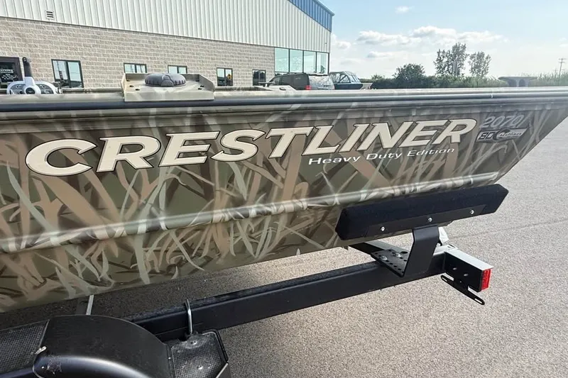 Slide: The Image of 2026 Crestliner 2070 Retriever SCHD boat with camouflage design, parked outdoors. - 14