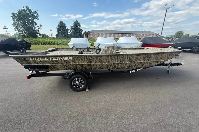 The Image of 2026 Crestliner 2070 Retriever SCHD boat with camouflage design on a trailer in a parking lot. - 0