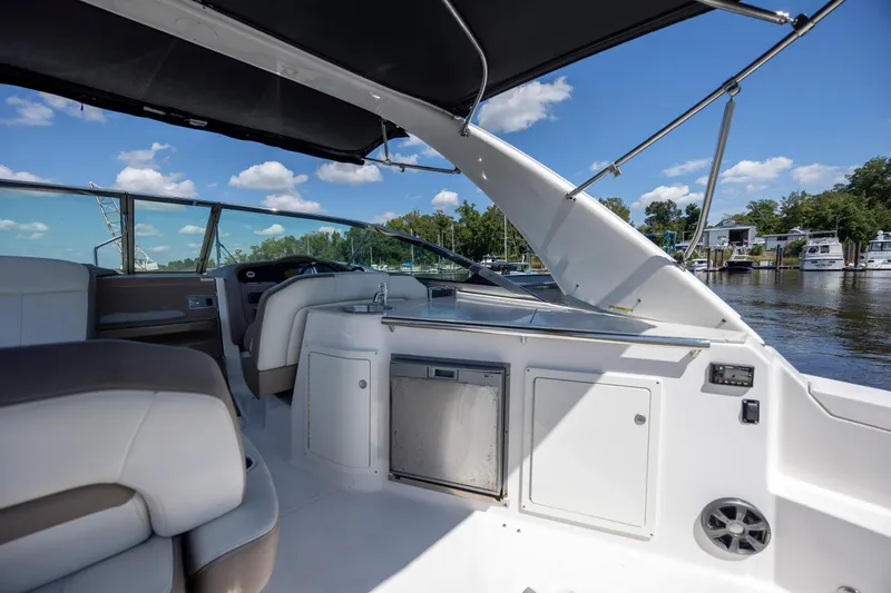 Slide: The Image of 2017 Regal 32 Express boat interior with seating, kitchenette, and water view. - 16