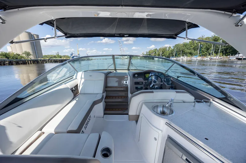 Slide: The Image of 2017 Regal 32 Express boat interior with helm, seating, and kitchenette on a sunny day. - 19