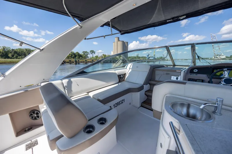 Slide: The Image of 2017 Regal 32 Express boat interior with seating, sink, and steering wheel, docked by a river. - 17