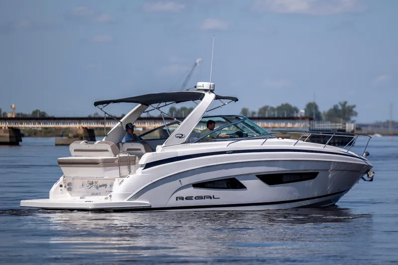 Slide: The Image of 2017 Regal 32 Express boat cruising on a calm river with bridge in background. - 4