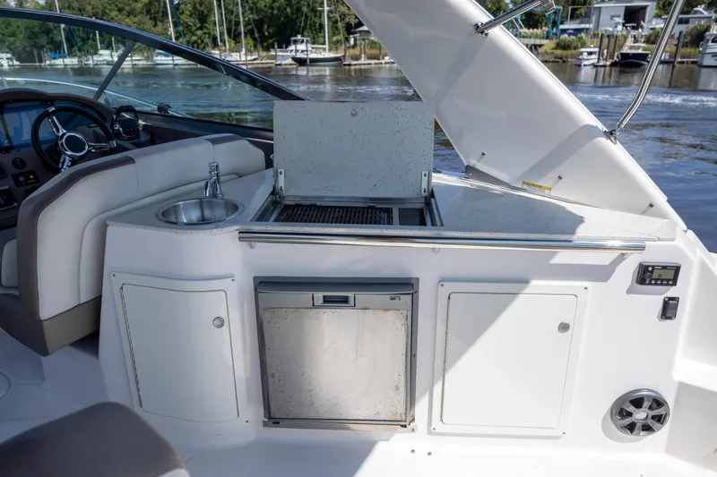 Slide: The Image of 2017 Regal 32 Express yacht interior with kitchenette and sink, docked by the water. - 11