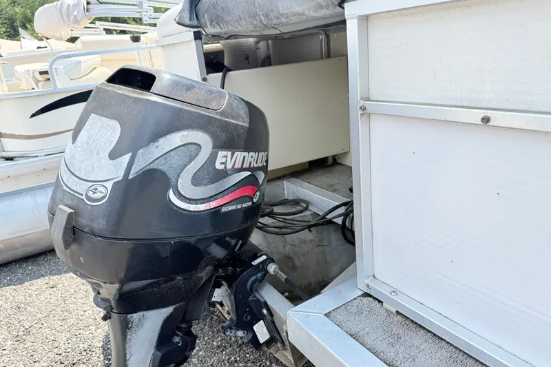 Slide: The Image of 2001 Harris Cruiser 220 boat with Evinrude outboard motor, docked on gravel surface. - 3