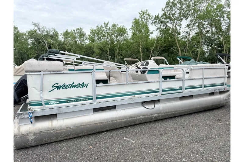 Slide: The Image of 1999 Sweetwater Challenger 220 ES pontoon boat parked on gravel with trees in background. - 2