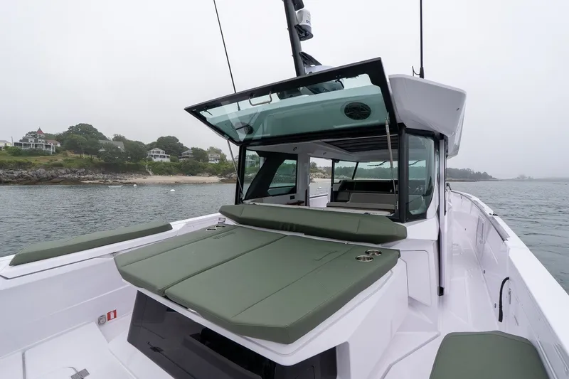 Slide: The Image of 2026 Axopar 38 Cross Cabin boat with green seating, docked near a scenic shoreline. - 20