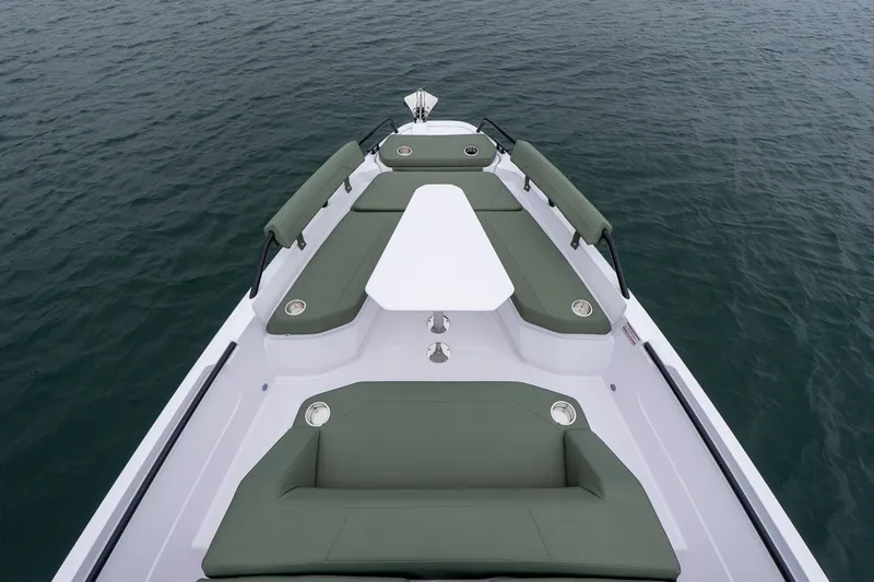 Slide: The Image of 2026 Axopar 38 Cross Cabin boat with green seating, white table, on calm water. - 10