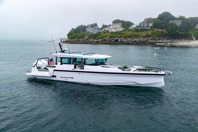 Slide: The Image of 2026 Axopar 38 Cross Cabin boat on calm water near a scenic coastline. - 2