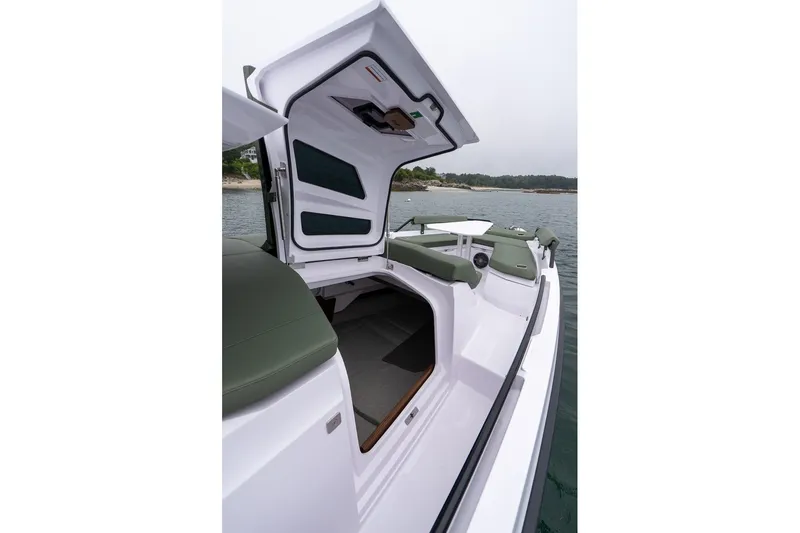 Slide: The Image of 2026 Axopar 38 Cross Cabin boat with open hatch, docked near a scenic shoreline. - 14