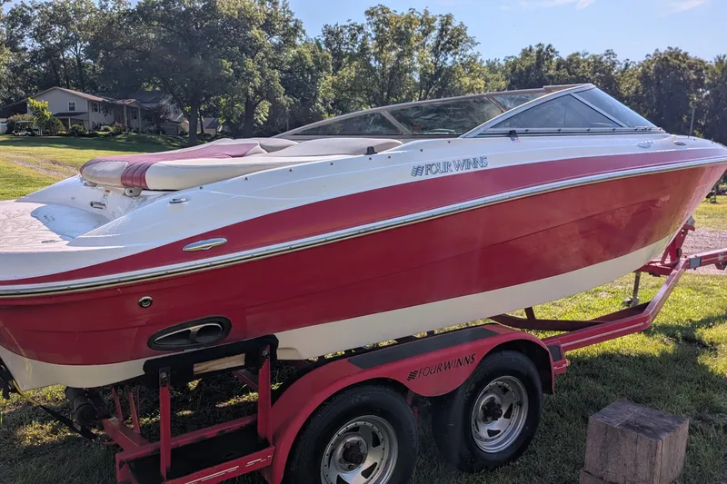 Slide: The Image of 2006 Four Winns 210 Horizon boat on trailer, red and white, parked on grass. - 4