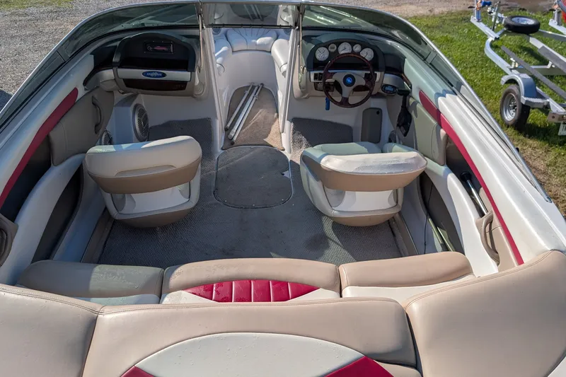 Slide: The Image of Interior of a 2006 Four Winns 210 Horizon boat, featuring beige and red seating. - 13