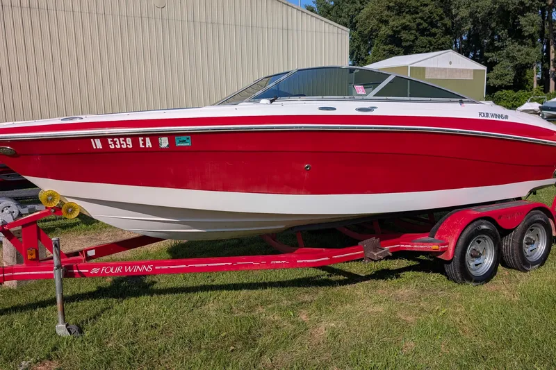 The Image of Red 2006 Four Winns 210 Horizon boat on trailer, parked on grass near a building. - 1