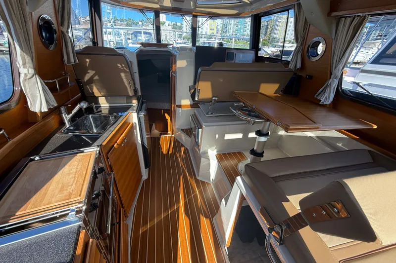 Slide: The Image of 2023 Ranger Tugs R-29 S interior with wood accents, kitchenette, and seating area. - 11