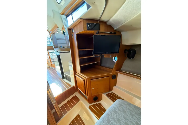 Slide: The Image of 2023 Ranger Tugs R-29 S interior with wooden cabinetry and mounted TV screen. - 13