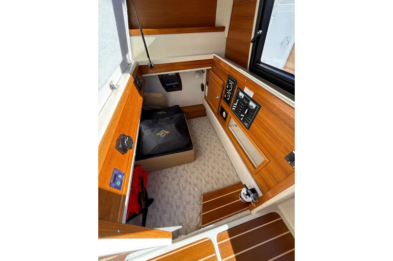 Slide: The Image of 2023 Ranger Tugs R-29 S cabin interior with wood paneling and control panels. - 14