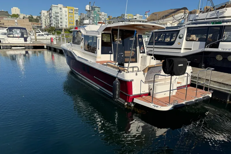 Slide: The Image of 2023 Ranger Tugs R-29 S docked at marina, surrounded by modern buildings. - 1