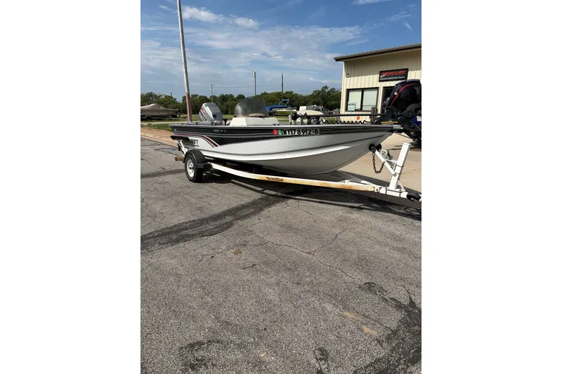 Slide: The Image of 1998 Alumacraft boat on trailer, parked outdoors near a building under a clear sky. - 7